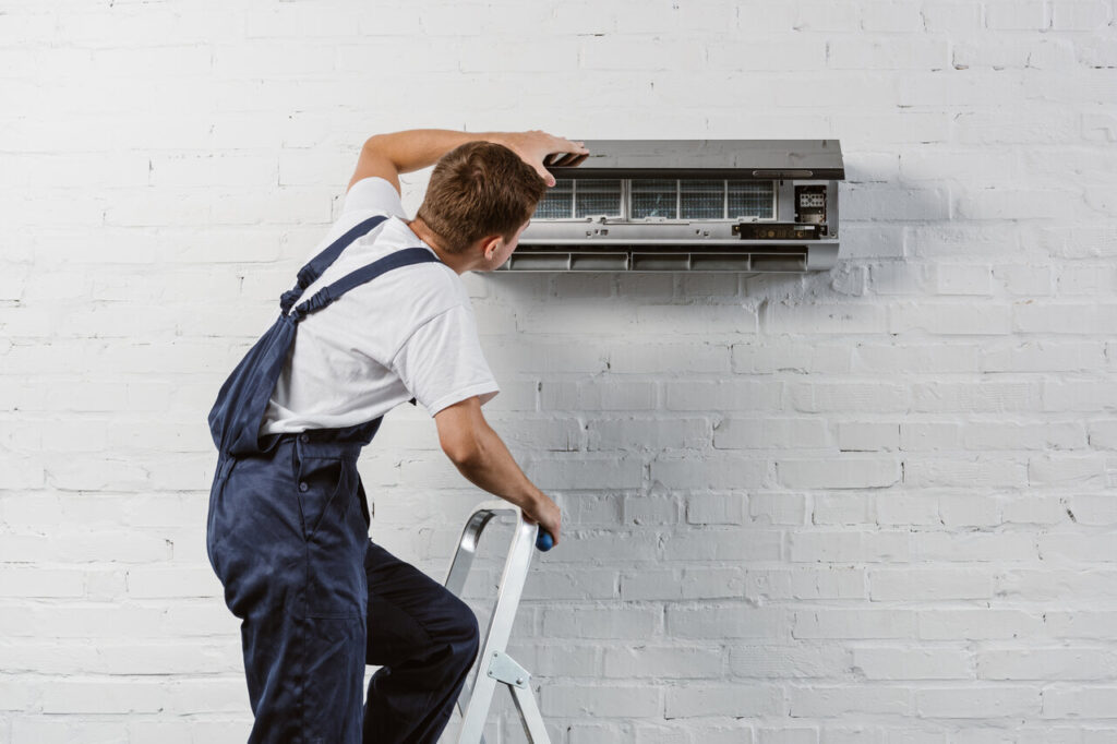 A man repairs an air conditioner, focused on fixing the unit.